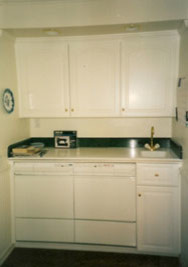 Inspiration for a mid-sized timeless u-shaped medium tone wood floor eat-in kitchen remodel in Orange County with an integrated sink, raised-panel cabinets, white cabinets, stone tile backsplash, white appliances, an island and solid surface countertops