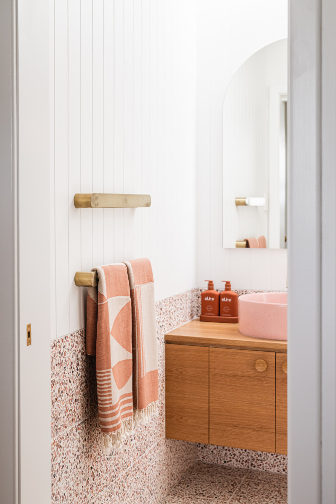 Inspiration for a mid-sized beach style bathroom in Adelaide with furniture-like cabinets, white tile, white walls, terrazzo floors, a vessel sink, wood benchtops, multi-coloured floor, brown benchtops, a single vanity, a floating vanity, decorative wall panelling and medium wood cabinets.