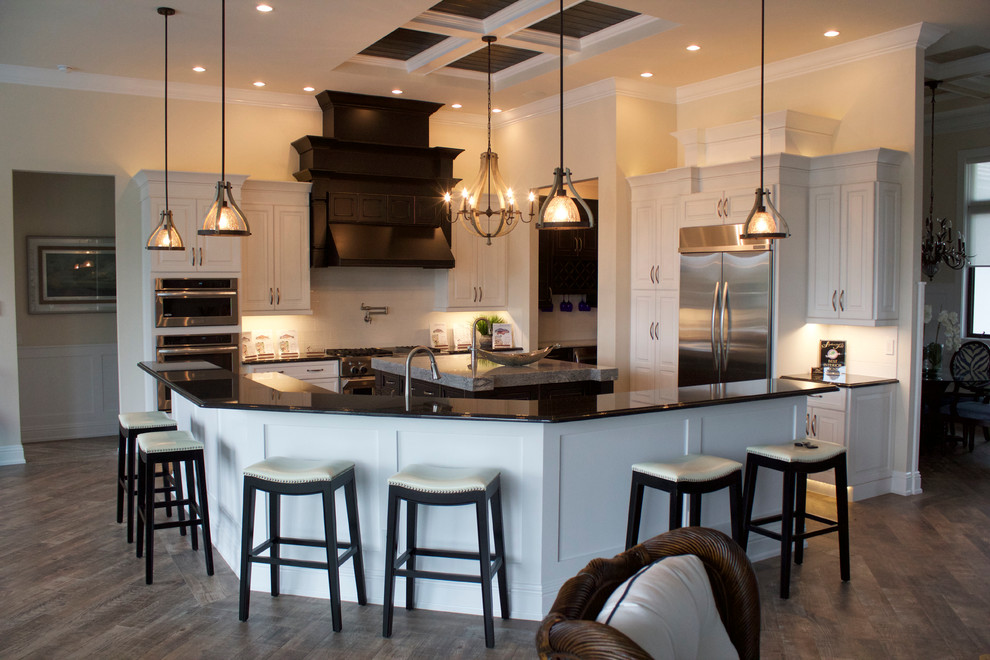 Inspiration for a large transitional u-shaped open plan kitchen in Miami with a farmhouse sink, raised-panel cabinets, distressed cabinets, quartz benchtops, white splashback, ceramic splashback, stainless steel appliances, medium hardwood floors and with island.