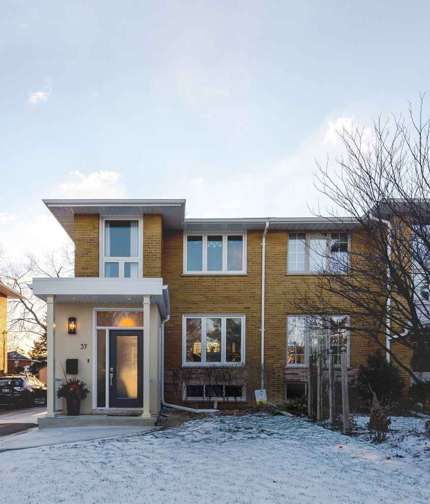 Example of a small transitional yellow two-story brick exterior home design in Toronto with a hip roof
