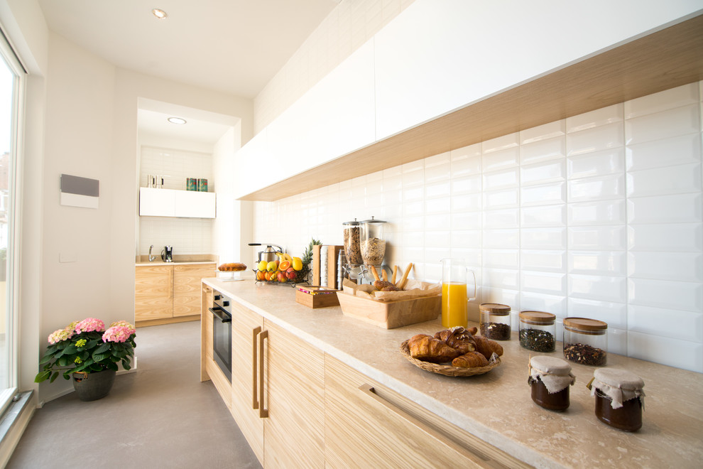 This is an example of a mid-sized scandinavian galley kitchen in Florence with flat-panel cabinets, light wood cabinets, limestone benchtops, white splashback and grey floor.