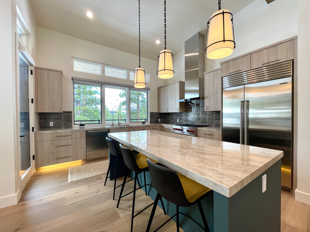 Example of a mid-sized minimalist l-shaped light wood floor and brown floor eat-in kitchen design with an undermount sink, flat-panel cabinets, brown cabinets, quartzite countertops, green backsplash, ceramic backsplash, stainless steel appliances, an island and beige countertops