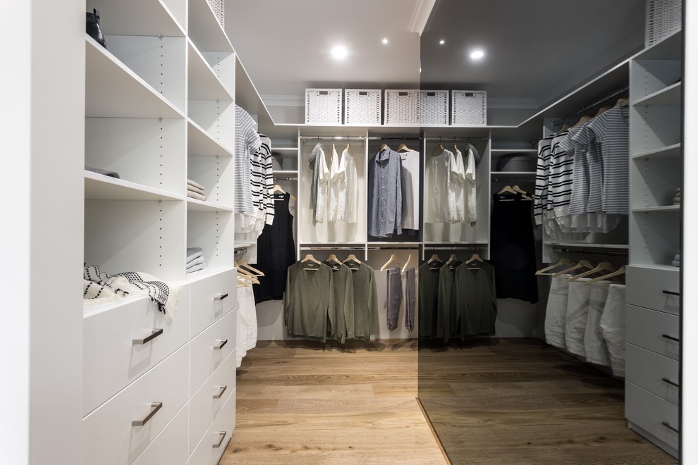 Inspiration for a contemporary gender-neutral walk-in wardrobe in Perth with flat-panel cabinets, white cabinets, medium hardwood floors and brown floor.