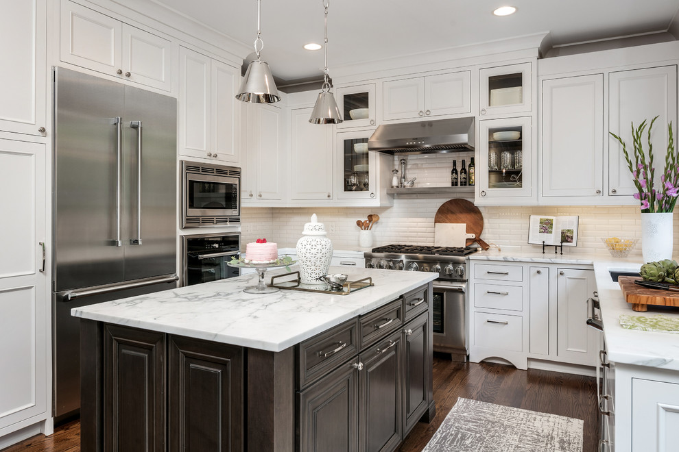 Design ideas for a transitional u-shaped kitchen in Detroit with an undermount sink, recessed-panel cabinets, white cabinets, white splashback, subway tile splashback, stainless steel appliances, dark hardwood floors, with island and brown floor.