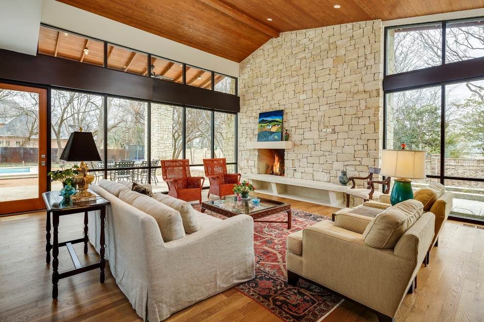 This is an example of a midcentury formal living room in Dallas with medium hardwood floors, a standard fireplace, a stone fireplace surround and no tv.