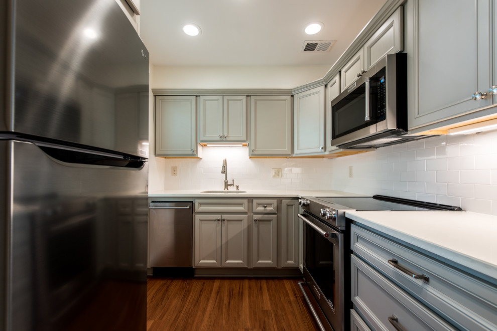Inspiration for a small transitional l-shaped vinyl floor and brown floor eat-in kitchen remodel in DC Metro with an undermount sink, shaker cabinets, gray cabinets, quartz countertops, white backsplash, porcelain backsplash, stainless steel appliances and no island
