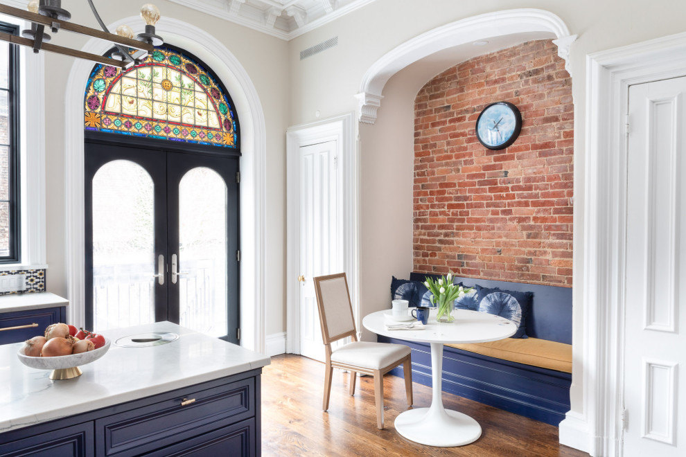 Foto på ett stort vintage vit l-kök, med en undermonterad diskho, luckor med infälld panel, blå skåp, bänkskiva i kvartsit, flerfärgad stänkskydd, stänkskydd i mosaik, integrerade vitvaror, mörkt trägolv, en köksö och brunt golv