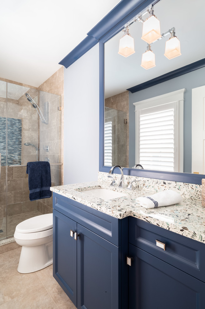 Photo of a mid-sized beach style kids bathroom in Philadelphia with recessed-panel cabinets, blue cabinets, a one-piece toilet, beige tile, marble, blue walls, marble floors, an undermount sink, quartzite benchtops, beige floor, a hinged shower door and multi-coloured benchtops.