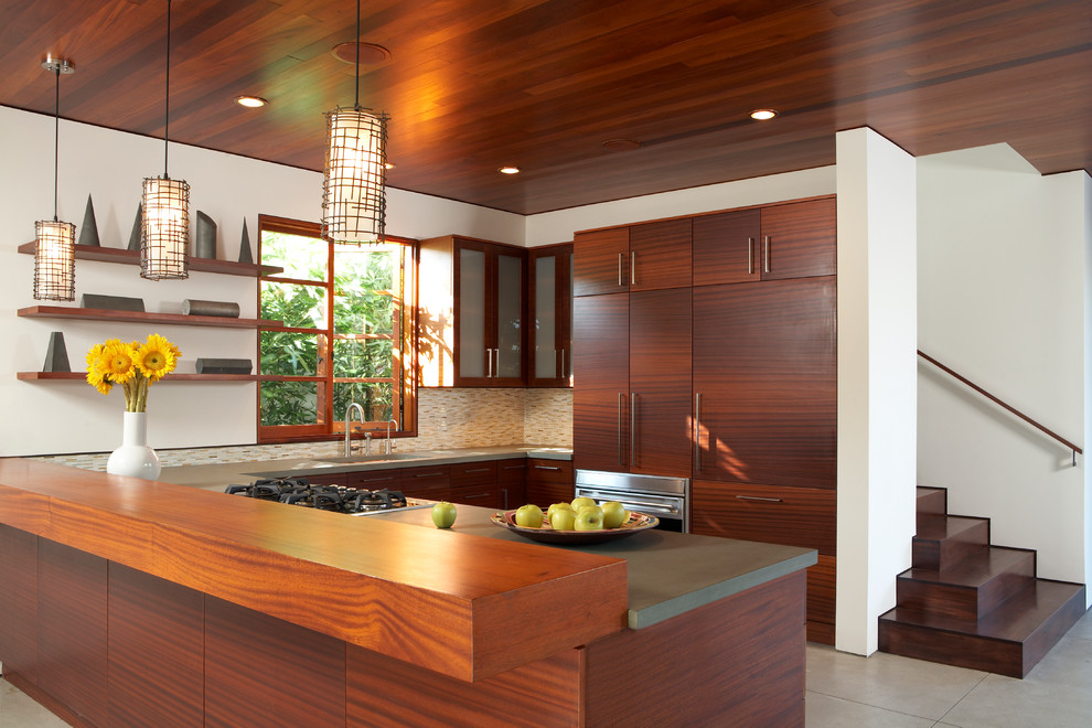 Photo of a contemporary u-shaped kitchen in Los Angeles with flat-panel cabinets, medium wood cabinets, multi-coloured splashback, mosaic tile splashback, panelled appliances and a peninsula.