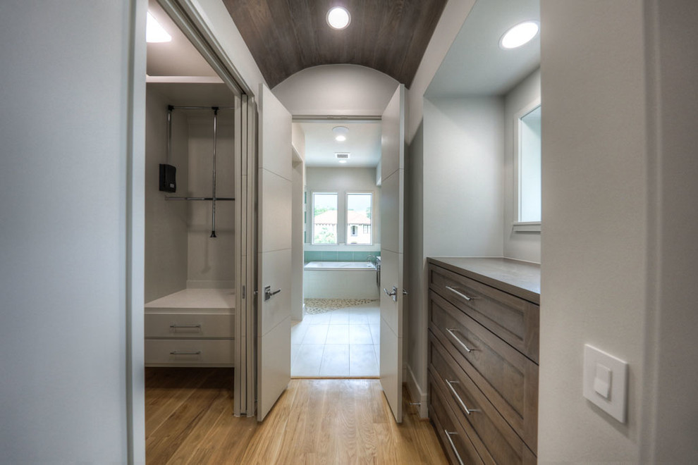 This is an example of a large contemporary gender-neutral walk-in wardrobe in San Francisco with shaker cabinets, distressed cabinets and light hardwood floors.