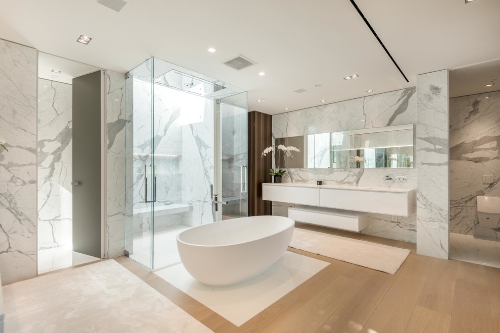 Design ideas for a contemporary master bathroom in Los Angeles with flat-panel cabinets, white cabinets, a freestanding tub, a curbless shower, a wall-mount toilet, white walls, light hardwood floors, beige floor and a hinged shower door.