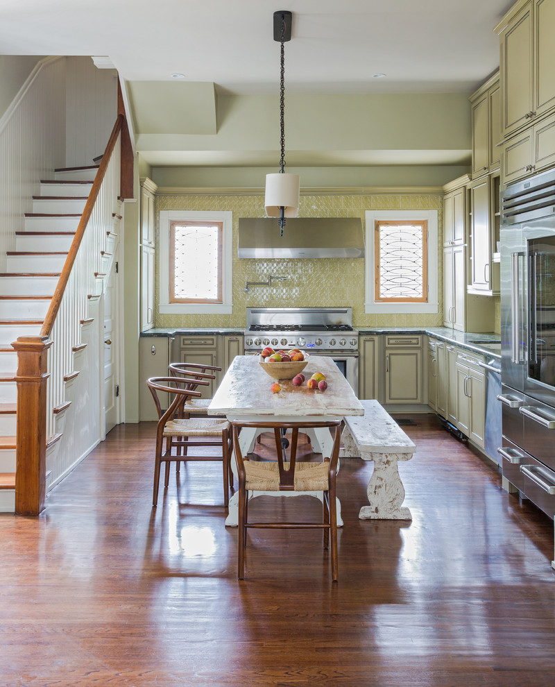 Photo of a traditional l-shaped eat-in kitchen in New Orleans with recessed-panel cabinets, green cabinets, green splashback, stainless steel appliances, medium hardwood floors and no island.