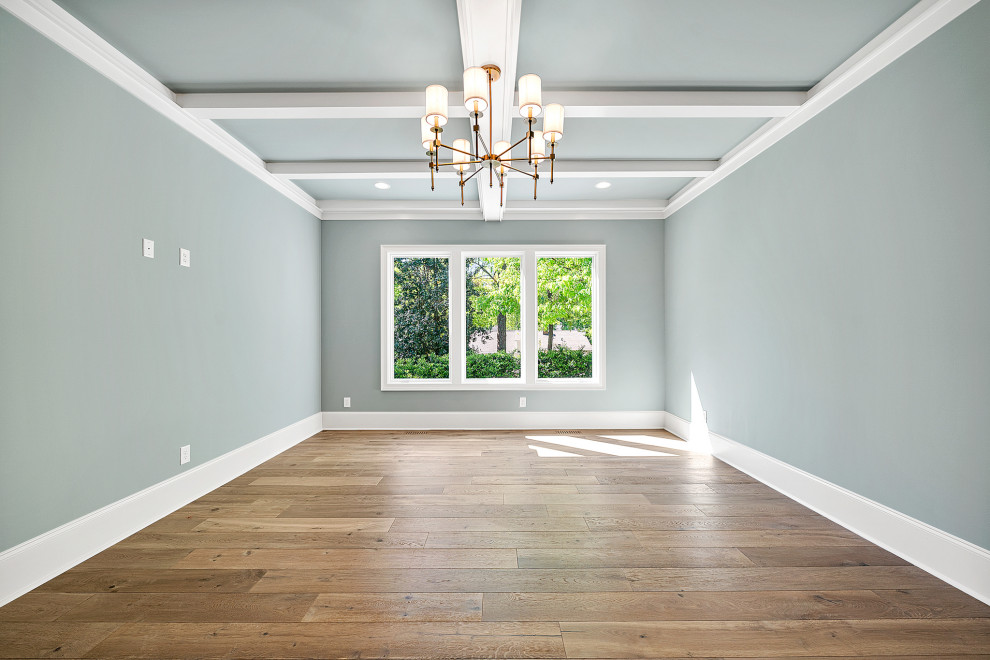 This is an example of a large traditional master bedroom in Raleigh with blue walls, medium hardwood floors, brown floor and coffered.