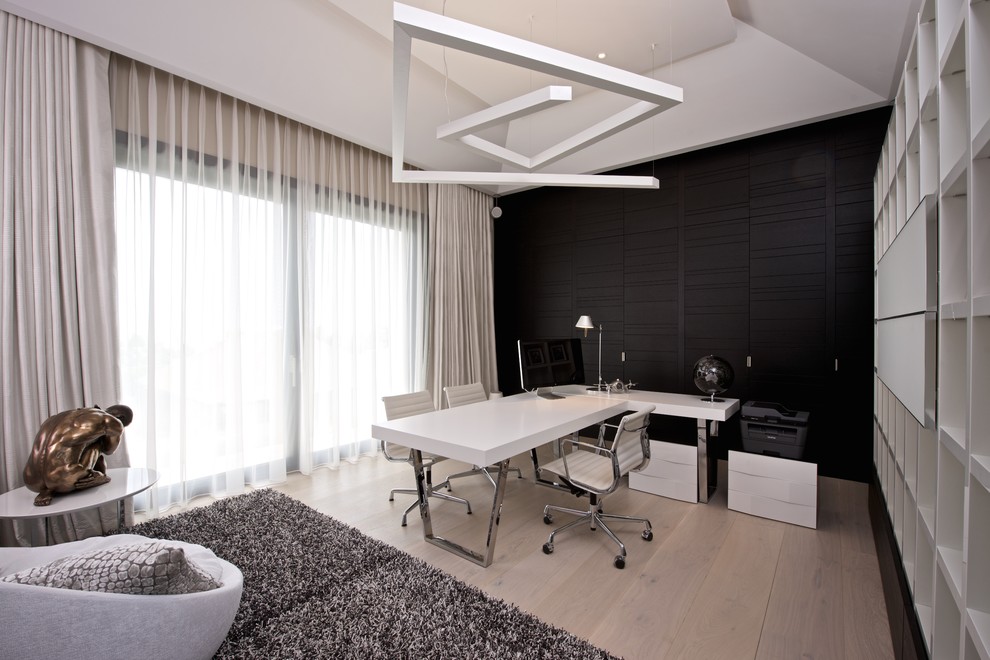 Photo of a mid-sized contemporary study room in Other with black walls, light hardwood floors, a freestanding desk and no fireplace.