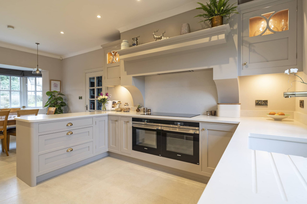 Photo of a medium sized traditional grey and white u-shaped kitchen/diner in Oxfordshire with a built-in sink, shaker cabinets, grey cabinets, quartz worktops, grey splashback, black appliances, ceramic flooring, no island, beige floors and grey worktops.
