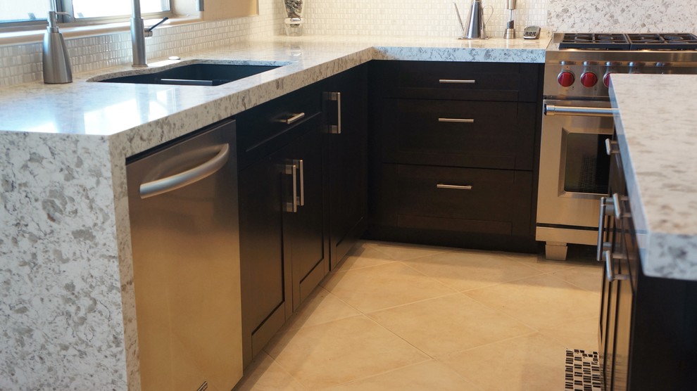 Transitional l-shaped porcelain tile and beige floor kitchen photo in Phoenix with an undermount sink, recessed-panel cabinets, dark wood cabinets, quartz countertops, white backsplash, ceramic backsplash, stainless steel appliances and an island
