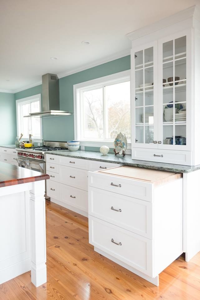 Photo of a mid-sized beach style galley eat-in kitchen in New York with a double-bowl sink, shaker cabinets, white cabinets, granite benchtops, blue splashback, stainless steel appliances, medium hardwood floors and with island.