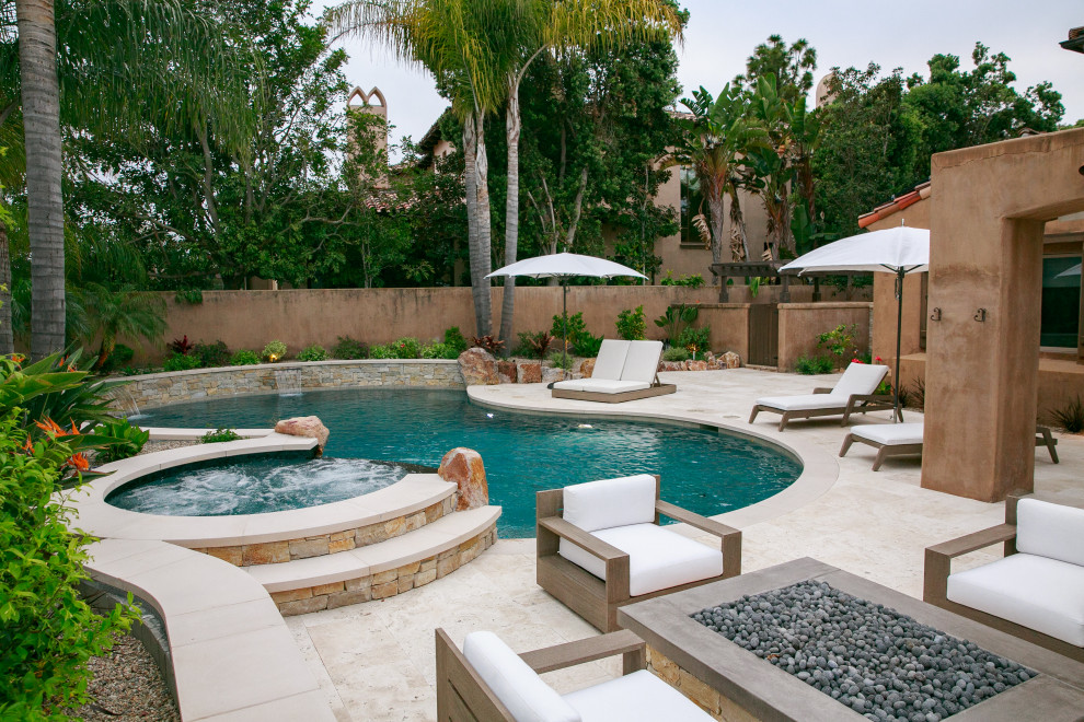 This is an example of a mid-sized transitional backyard custom-shaped pool in San Diego with natural stone pavers.