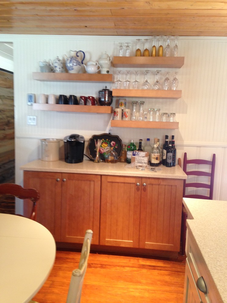 Example of a mid-sized mountain style l-shaped medium tone wood floor open concept kitchen design with a farmhouse sink, beaded inset cabinets, light wood cabinets, solid surface countertops, beige backsplash, glass tile backsplash, stainless steel appliances and an island