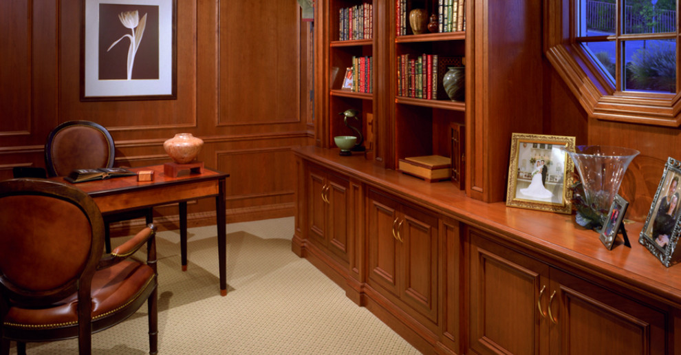 Inspiration för stora klassiska hemmabibliotek, med bruna väggar, heltäckningsmatta och ett fristående skrivbord