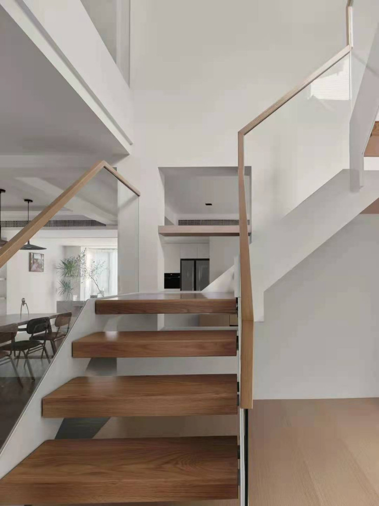 Стильный дизайн: п-образная лестница среднего размера в стиле модернизм с деревянными ступенями, стеклянными перилами и панелями на части стены без подступенок - последний тренд