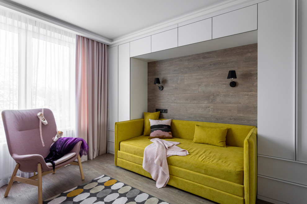 This is an example of a mid-sized contemporary kids' bedroom for kids 4-10 years old and girls in Yekaterinburg with pink walls, laminate floors and brown floor.