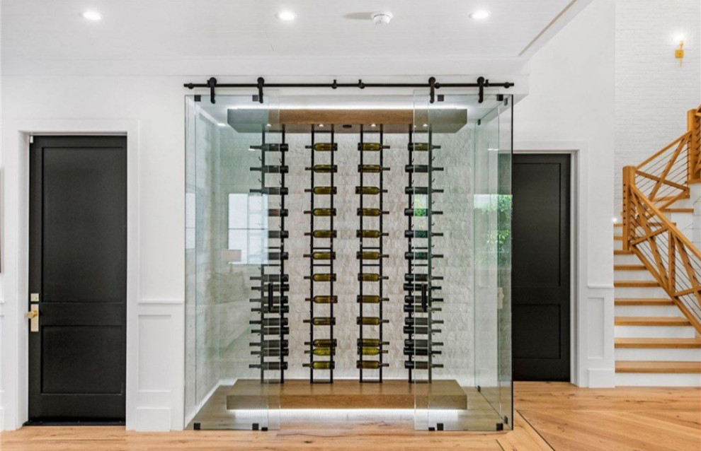 Photo of a mid-sized modern wine cellar with light hardwood floors, storage racks and brown floor.