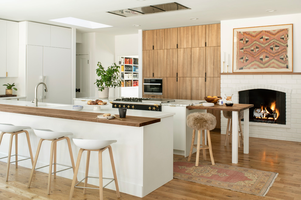 Inspiration for a scandinavian u-shaped kitchen in Denver with an undermount sink, flat-panel cabinets, medium wood cabinets, black appliances, medium hardwood floors, with island, brown floor and white benchtop.