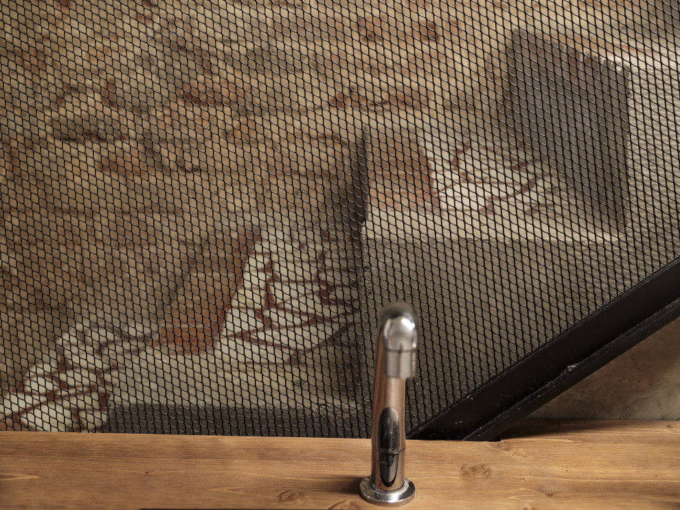 Diseño de bar en casa con barra de bar lineal de tamaño medio con fregadero encastrado, armarios con paneles lisos, puertas de armario de madera en tonos medios, encimera de madera, salpicadero negro, salpicadero de metal, suelo de cemento, suelo gris y encimeras marrones