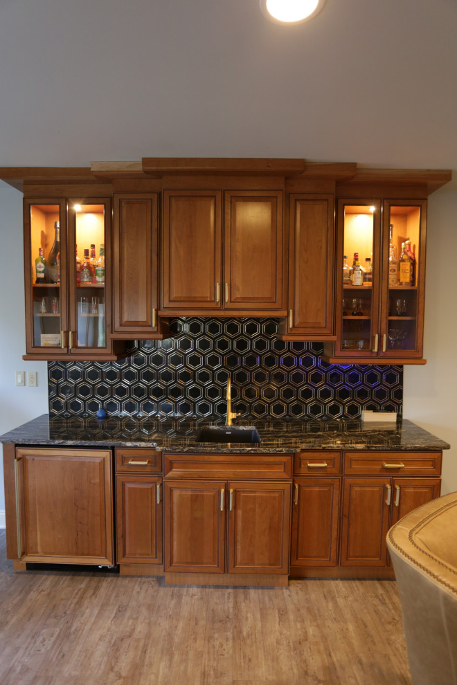 Design ideas for a mid-sized traditional single-wall wet bar in Baltimore with an undermount sink, raised-panel cabinets, medium wood cabinets, granite benchtops, black splashback, marble splashback, plywood floors, beige floor and black benchtop.