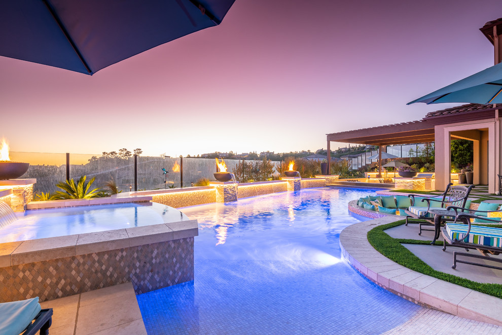 This is an example of a large contemporary backyard custom-shaped lap pool in Orange County with a hot tub and tile.