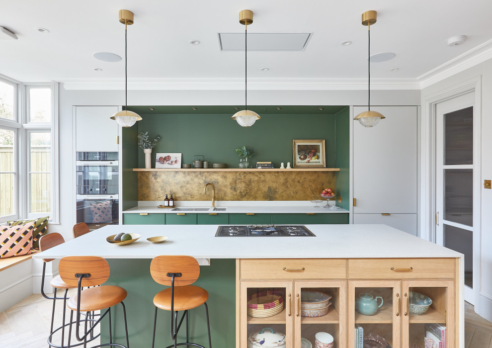 This is an example of a large scandinavian galley eat-in kitchen in London with an undermount sink, flat-panel cabinets, green cabinets, quartzite benchtops, metallic splashback, metal splashback, panelled appliances, light hardwood floors, with island, beige floor, white benchtop and wood.