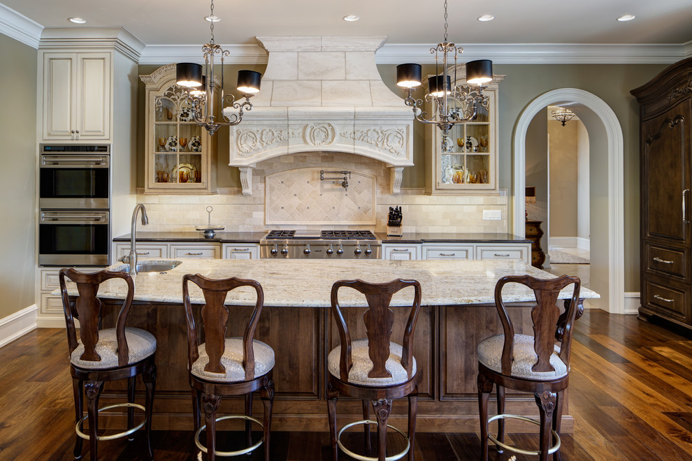 Traditional galley kitchen in Chicago with an undermount sink, raised-panel cabinets, medium wood cabinets, beige splashback, stainless steel appliances, medium hardwood floors, with island, brown floor and beige benchtop.