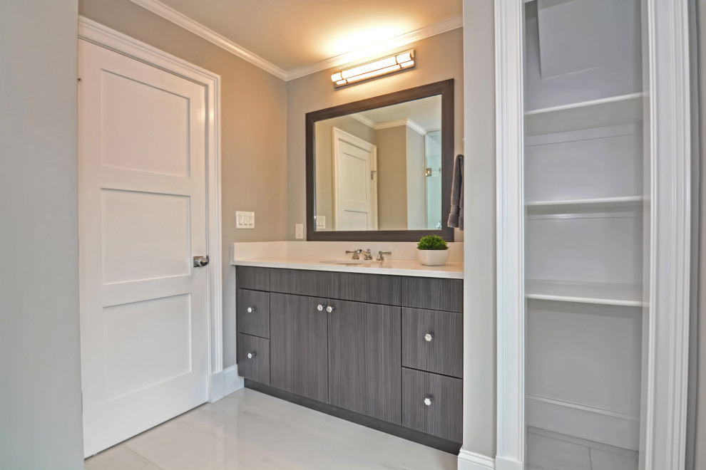 This is an example of a medium sized traditional shower room bathroom in Boston with flat-panel cabinets, dark wood cabinets, an alcove shower, a two-piece toilet, white tiles, porcelain tiles, beige walls, porcelain flooring, a submerged sink, engineered stone worktops, white floors, a hinged door, white worktops, a single sink and a built in vanity unit.