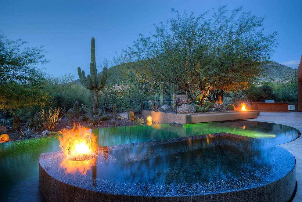 This is an example of a large backyard custom-shaped infinity pool in Phoenix with a hot tub.