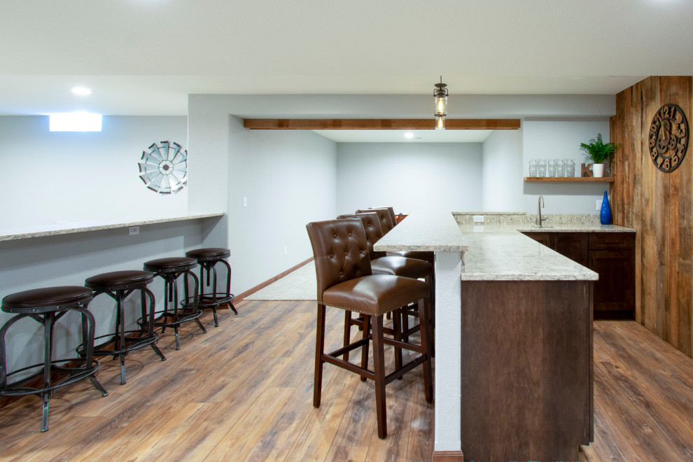 Design ideas for an expansive transitional fully buried basement in Milwaukee with a home bar, grey walls, vinyl floors, beige floor, exposed beam and wood walls.