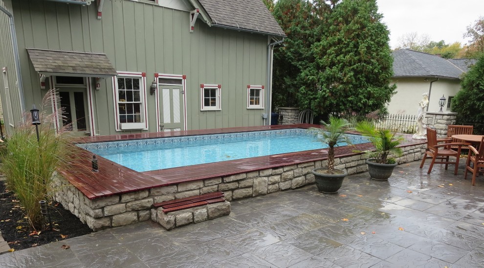 Example of a mid-sized transitional backyard rectangular aboveground pool design in Columbus with decking