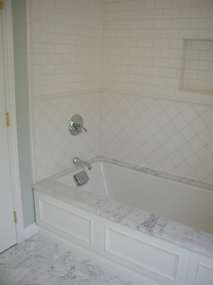 This is an example of a small traditional kids bathroom in Los Angeles with recessed-panel cabinets, white cabinets, an undermount tub, white tile, ceramic tile, blue walls, marble floors and marble benchtops.