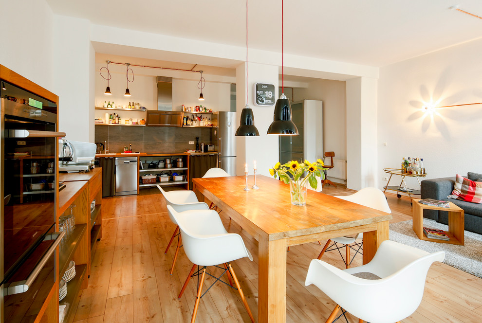 Photo of an industrial open plan dining in Cologne with white walls and light hardwood floors.