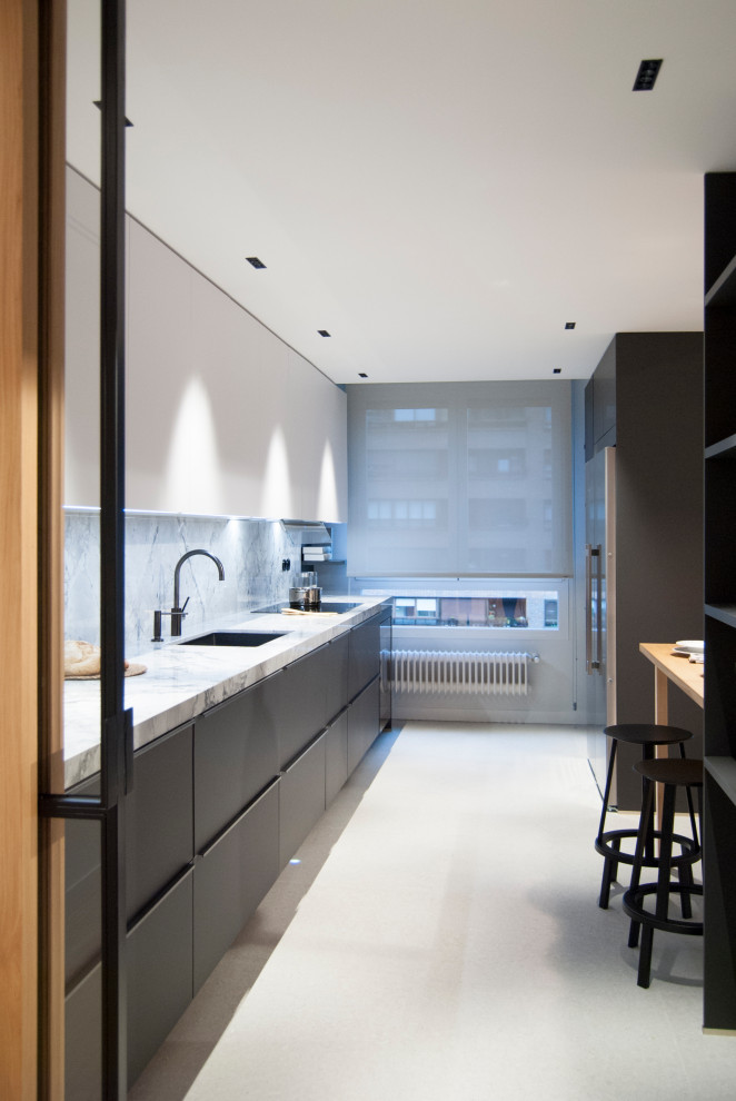Medium sized modern grey and black open plan kitchen in Bilbao with a submerged sink, flat-panel cabinets, grey cabinets, marble worktops, white splashback, marble splashback, black appliances, no island, beige floors and white worktops.