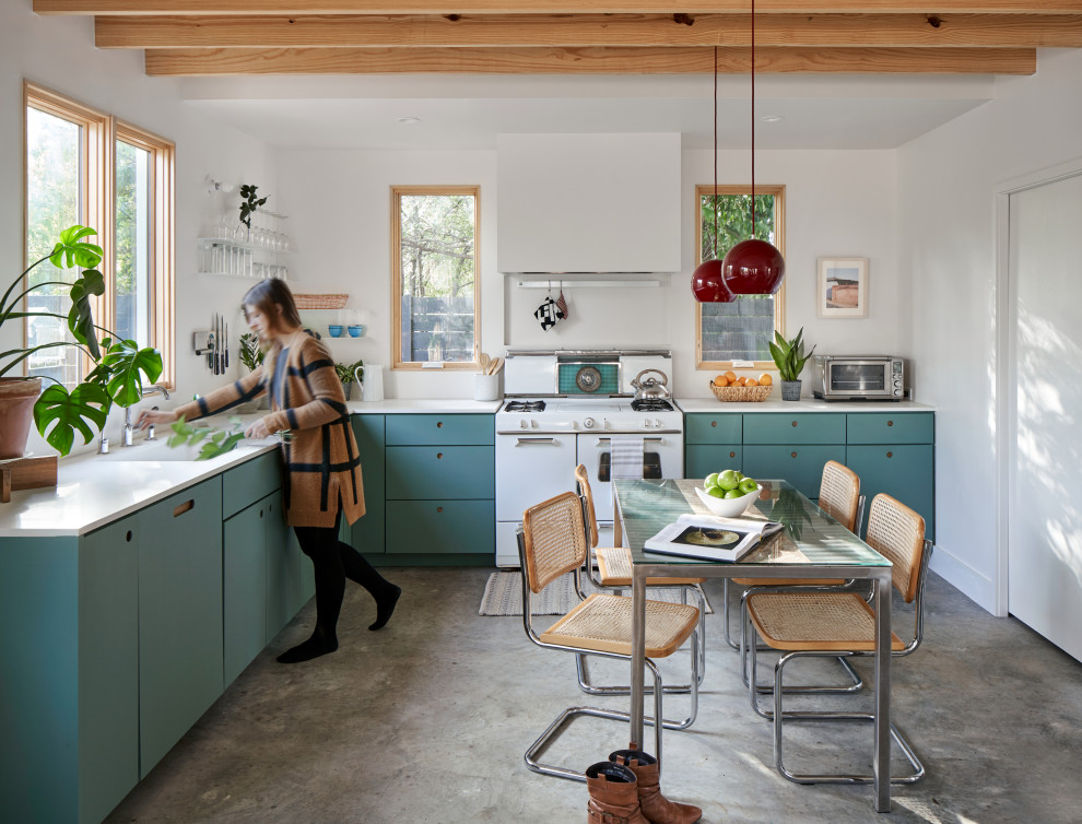 This is an example of a mid-sized eclectic l-shaped kitchen in Austin with an undermount sink, flat-panel cabinets, green cabinets, quartz benchtops, white appliances, concrete floors, no island, grey floor and white benchtop.