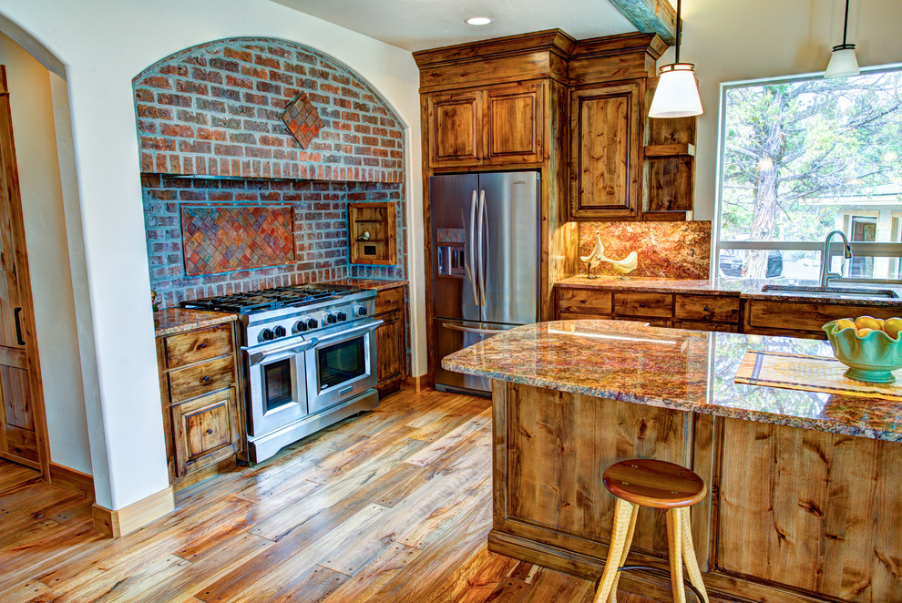 Example of a large mountain style u-shaped medium tone wood floor kitchen pantry design with a drop-in sink, glass-front cabinets, medium tone wood cabinets, beige backsplash, stainless steel appliances and an island