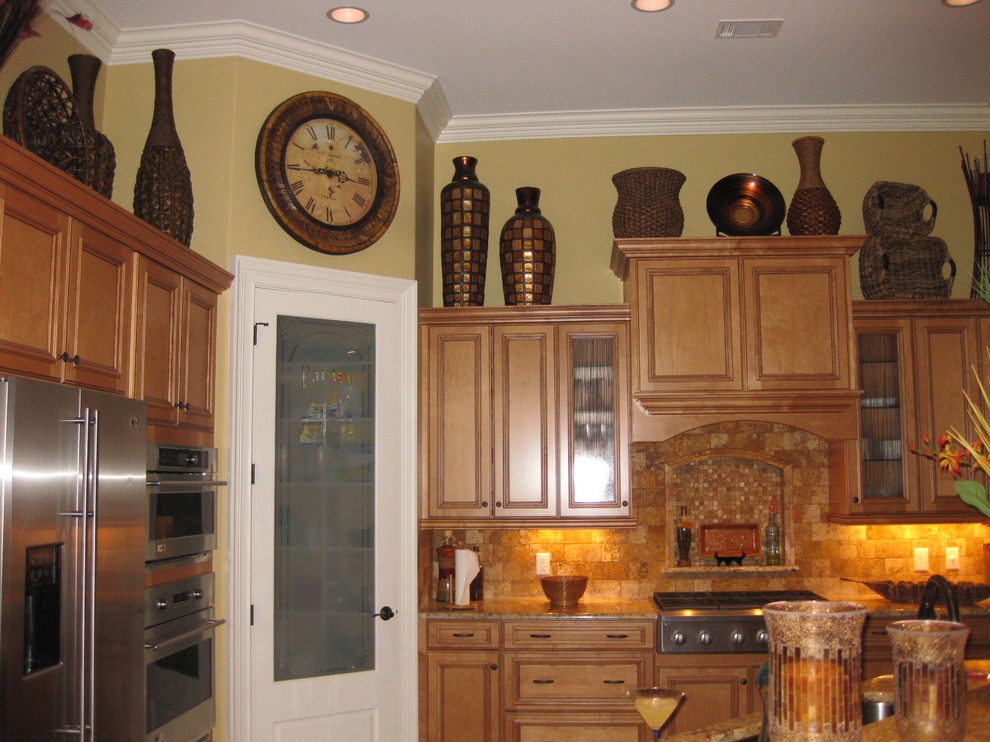 This is an example of a large beach style u-shaped kitchen pantry in Atlanta with a double-bowl sink, recessed-panel cabinets, light wood cabinets, granite benchtops, metallic splashback, stainless steel appliances, medium hardwood floors and with island.