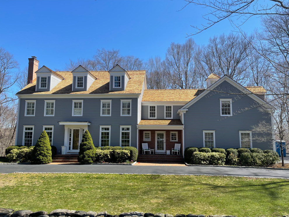 Cette photo montre une très grande façade de maison grise chic en bois et bardage à clin à deux étages et plus avec un toit à deux pans, un toit en shingle et un toit rouge.