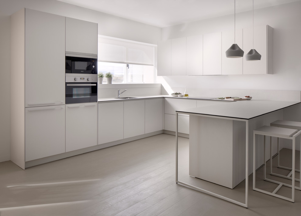 This is an example of a mid-sized contemporary u-shaped open plan kitchen in Other with an undermount sink, flat-panel cabinets, white cabinets, stainless steel appliances and no island.