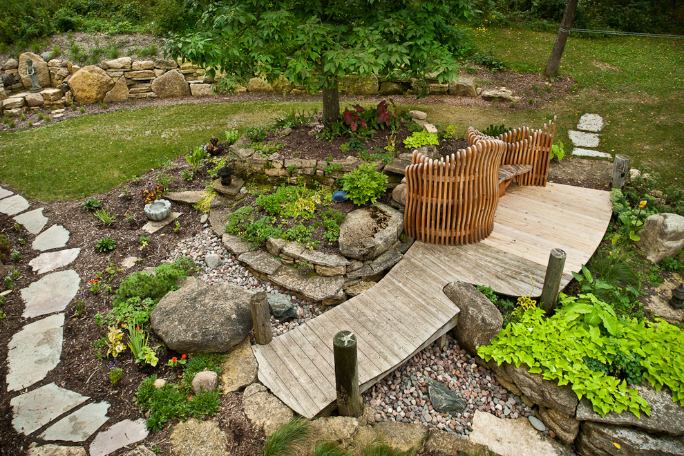 Inspiration for a mid-sized eclectic backyard full sun garden for summer in Other with a water feature, decking and a stone fence.