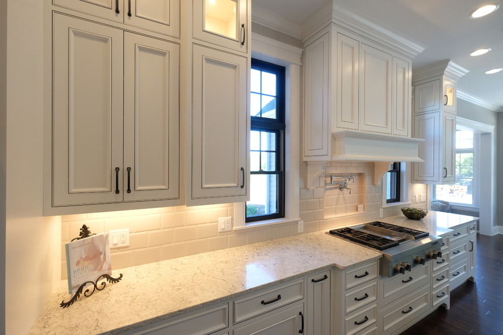 Inspiration for a large transitional single-wall dark wood floor and brown floor eat-in kitchen remodel with recessed-panel cabinets, white cabinets, quartz countertops, white backsplash and stainless steel appliances