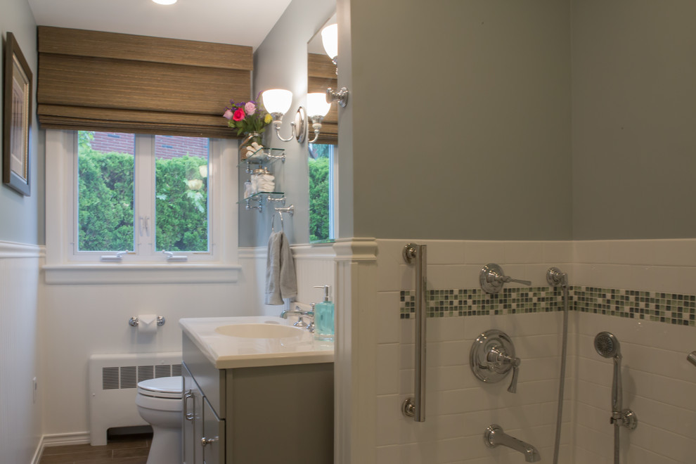 Photo of a mid-sized beach style master bathroom in Boston with shaker cabinets, grey cabinets, solid surface benchtops, white tile, subway tile and ceramic floors.