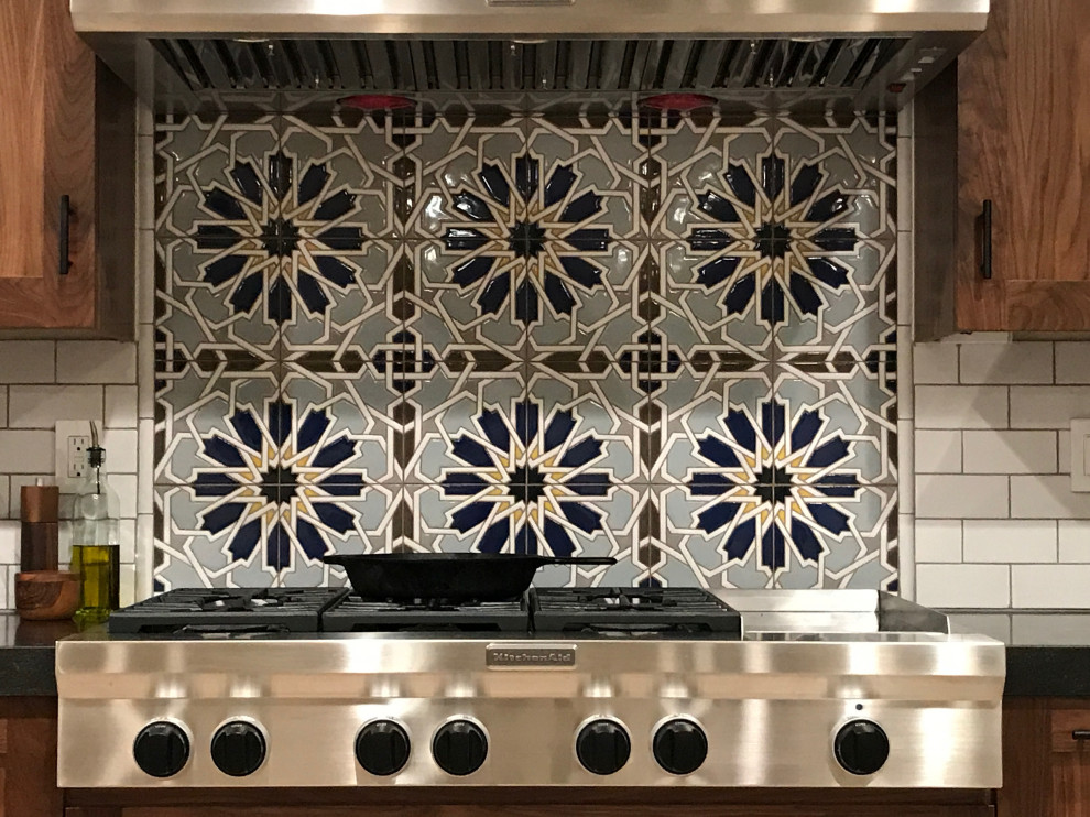 Example of a large arts and crafts l-shaped ceramic tile and beige floor eat-in kitchen design with an undermount sink, flat-panel cabinets, medium tone wood cabinets, granite countertops, white backsplash, ceramic backsplash, stainless steel appliances, an island and black countertops