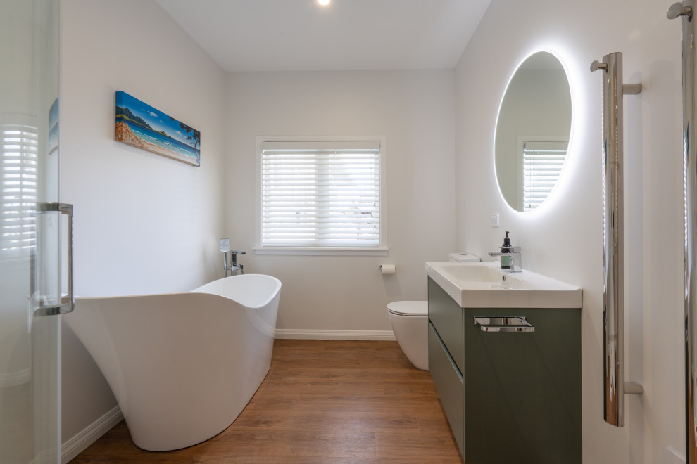 Example of a mid-sized transitional kids' white tile laminate floor, brown floor and single-sink bathroom design in Auckland with furniture-like cabinets, a one-piece toilet, white walls and a floating vanity